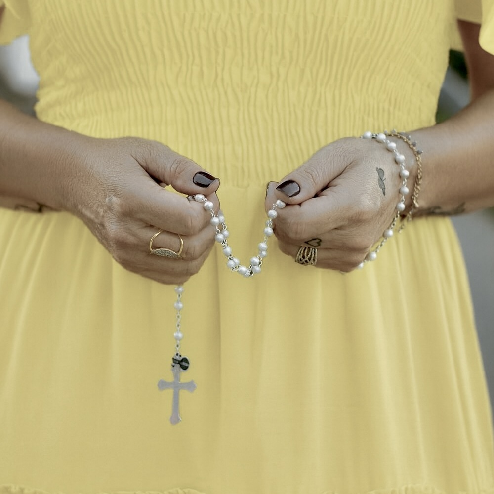 Woman in yellow dress holding a rosary